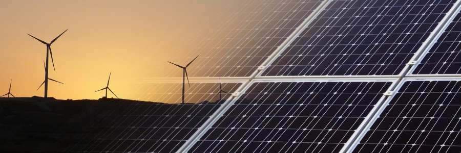 An image of wind turbines at sunset that fades left to right into an image of solar panels